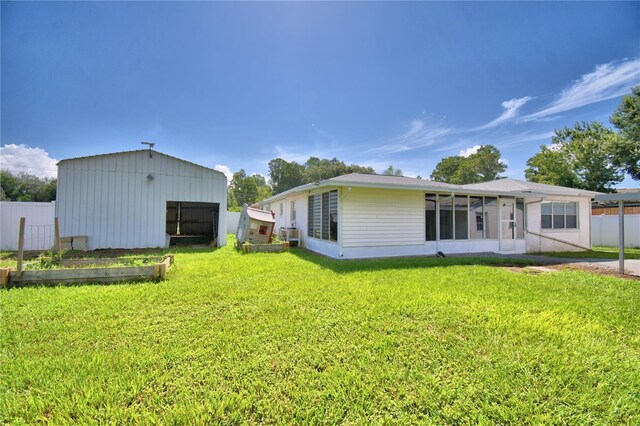 back of property with a lawn and an outdoor structure