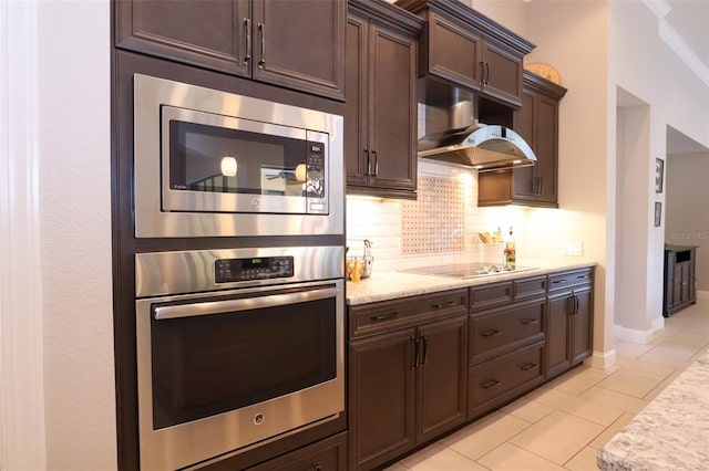 kitchen with range hood, stainless steel appliances, decorative backsplash, dark brown cabinets, and light stone countertops