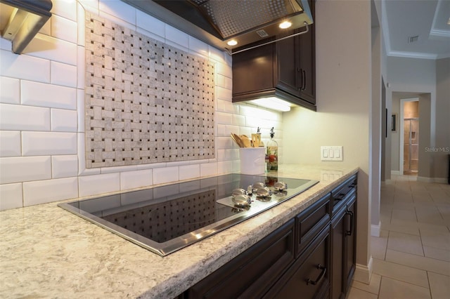 kitchen with light tile patterned floors, crown molding, dark brown cabinets, black electric cooktop, and decorative backsplash