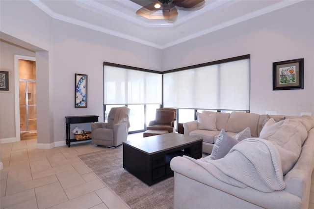 living room with ceiling fan, a raised ceiling, crown molding, and tile patterned floors