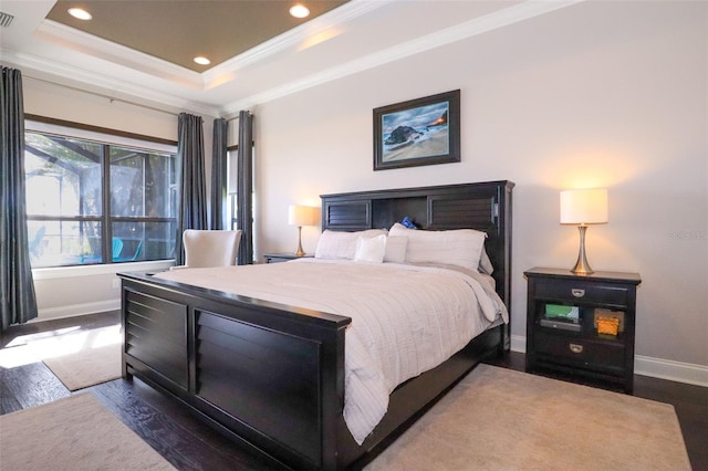 bedroom featuring crown molding, dark hardwood / wood-style floors, and a tray ceiling