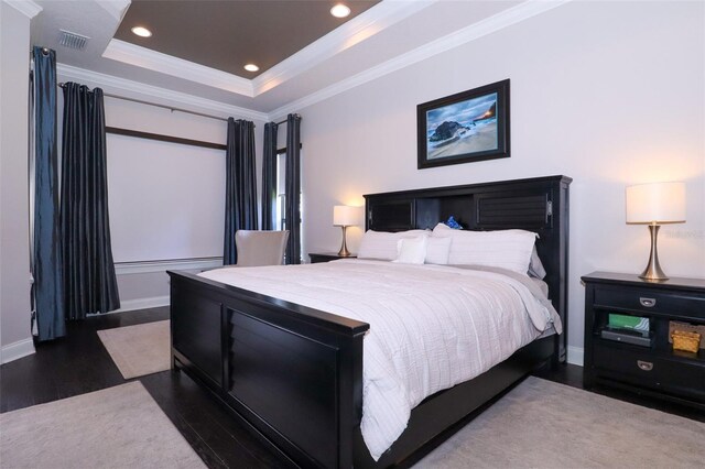 bedroom featuring crown molding, a raised ceiling, and dark hardwood / wood-style flooring