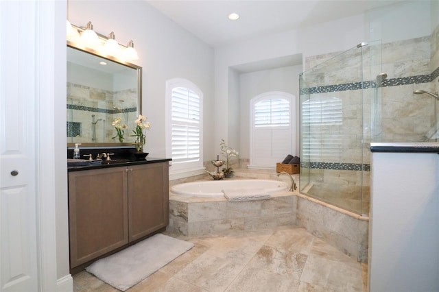 bathroom with a stall shower, a bath, and vanity