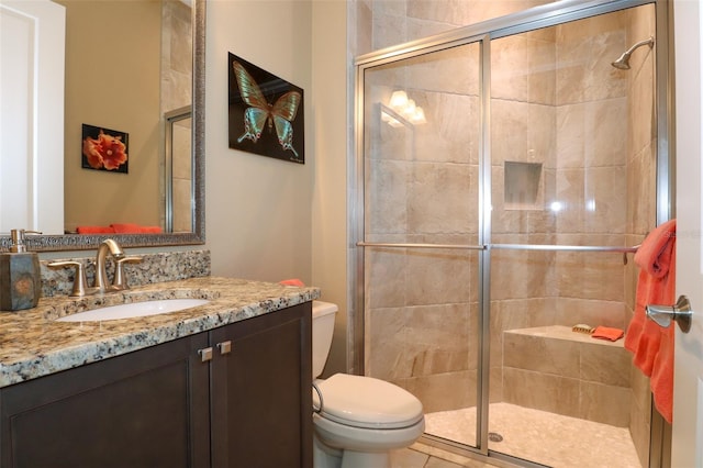 bathroom featuring vanity, toilet, a shower with shower door, and tile patterned flooring