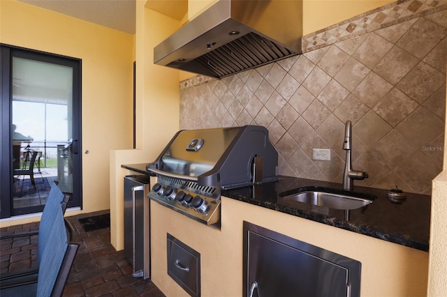 kitchen with sink, wall chimney range hood, and tasteful backsplash