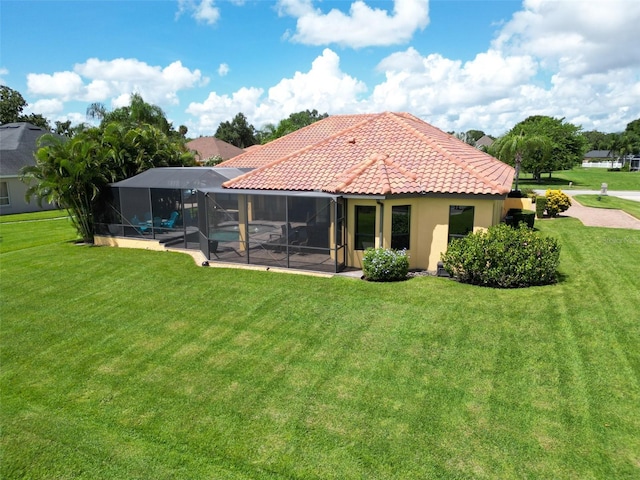 back of house with a lanai, a tile roof, a lawn, and stucco siding