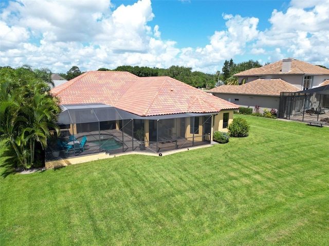 rear view of property with a tiled roof, a lawn, a lanai, and an outdoor pool