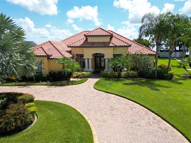 mediterranean / spanish home with a tiled roof, a front lawn, and stucco siding