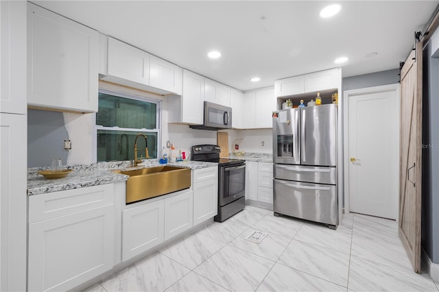 kitchen featuring stainless steel appliances, white cabinetry, a sink, and a barn door