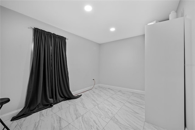 spare room featuring marble finish floor, recessed lighting, and baseboards