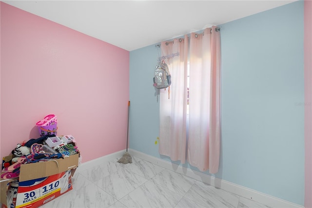 bedroom featuring marble finish floor and baseboards