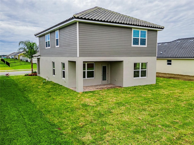 back of house featuring a lawn and a patio area