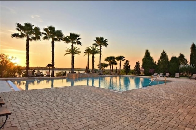 pool at dusk featuring a patio