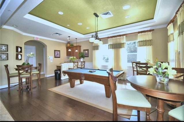 recreation room with a raised ceiling, arched walkways, crown molding, and wood finished floors