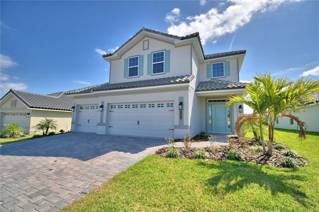 view of front of house featuring stucco siding, a tiled roof, decorative driveway, a front yard, and a garage