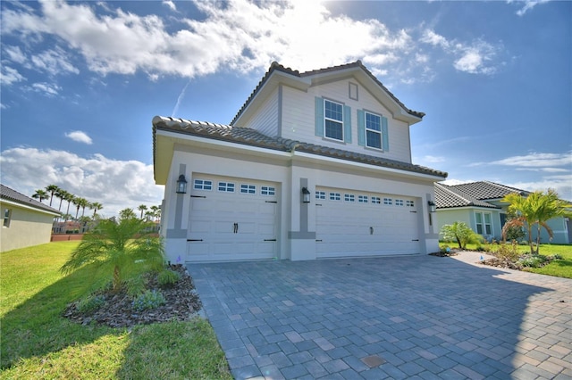 view of front of home with a front yard, decorative driveway, and an attached garage