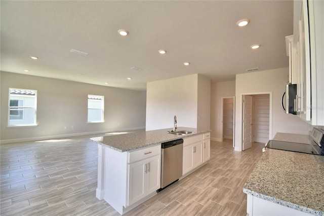 kitchen featuring white cabinets, appliances with stainless steel finishes, a sink, an island with sink, and open floor plan