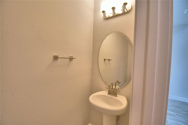 bathroom with baseboards, wood finished floors, and a sink