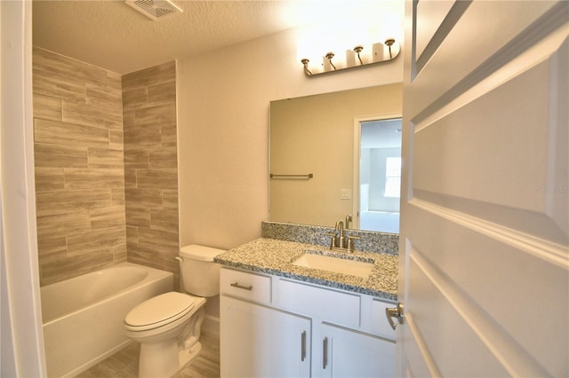 bathroom with vanity, toilet, a textured ceiling, visible vents, and wood finished floors