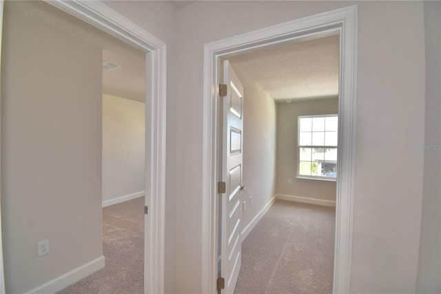 hallway with carpet, baseboards, and visible vents
