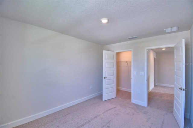 unfurnished bedroom with light carpet, a textured ceiling, baseboards, and visible vents