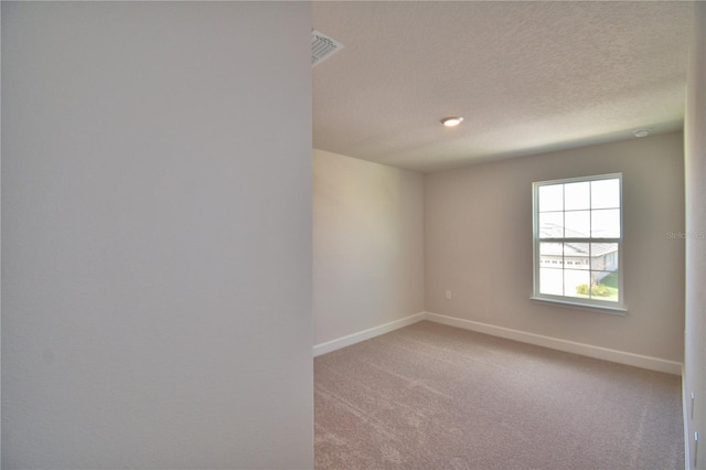 empty room with visible vents, baseboards, light colored carpet, and a textured ceiling