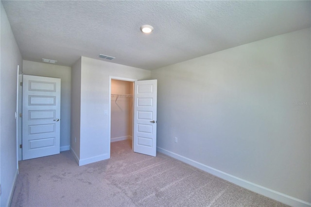 unfurnished bedroom with carpet floors, a closet, baseboards, and a textured ceiling