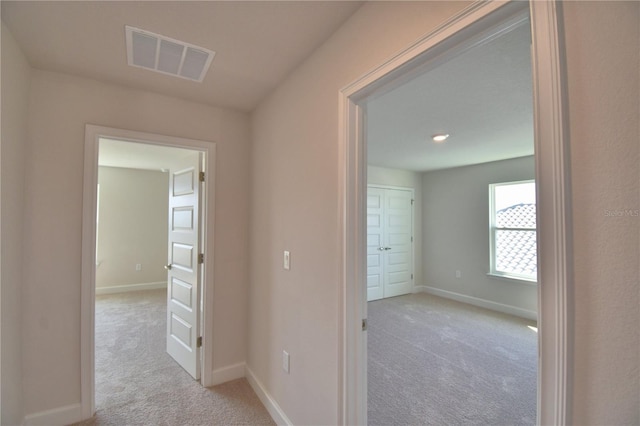 hall featuring baseboards, visible vents, and carpet