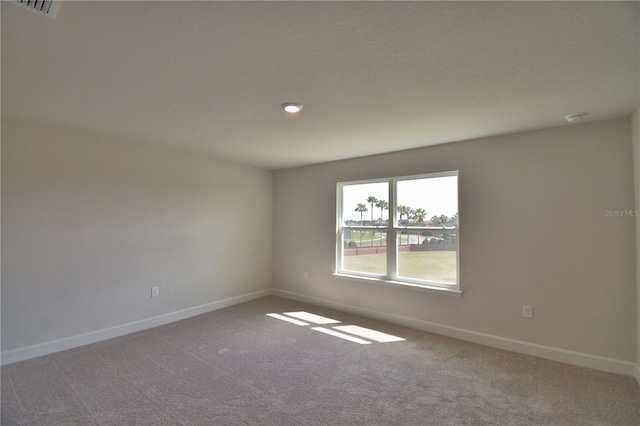 empty room with baseboards, visible vents, and carpet