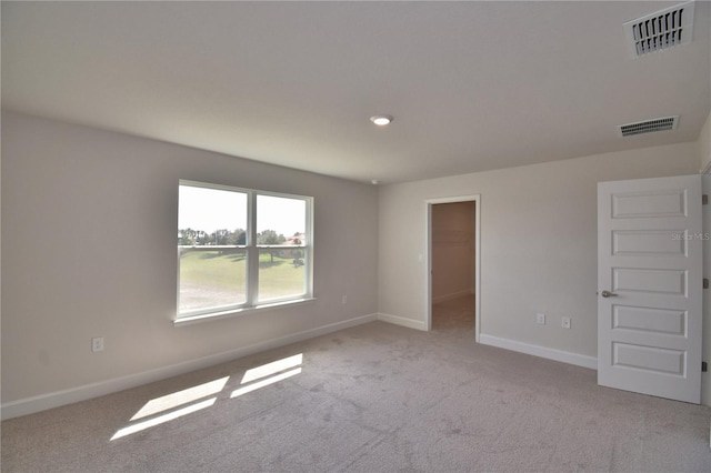 spare room featuring baseboards, visible vents, and light colored carpet