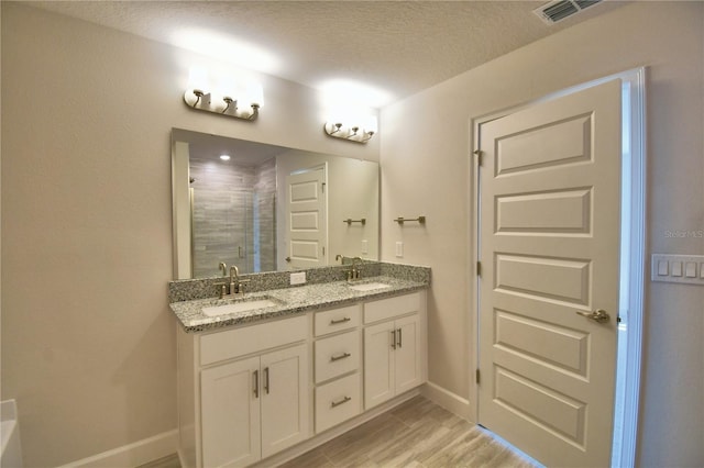 full bathroom with a stall shower, double vanity, visible vents, and a sink