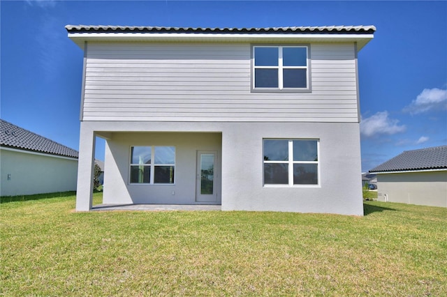 back of property with a lawn and stucco siding