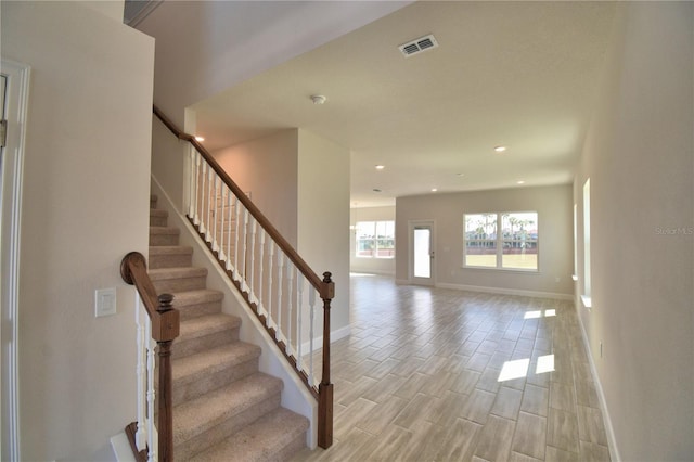 staircase featuring baseboards, visible vents, wood finished floors, and recessed lighting