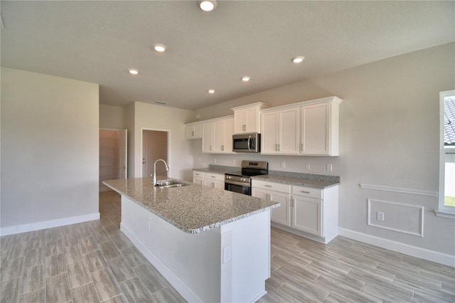 kitchen featuring white cabinetry, a sink, stainless steel appliances, and a center island with sink