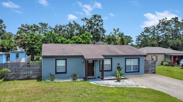 ranch-style home with concrete driveway, fence, stucco siding, and a front yard