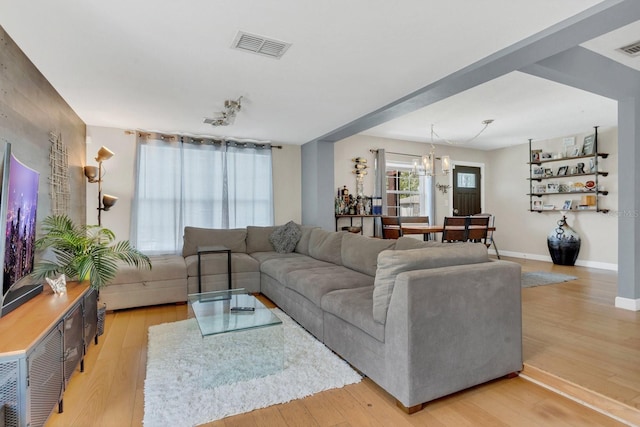 living area with light wood-style flooring, baseboards, an inviting chandelier, and visible vents