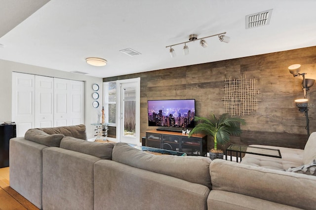 living area with visible vents, wood finished floors, and wooden walls