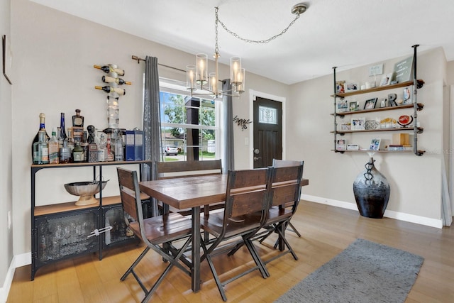 dining room with baseboards, an inviting chandelier, and wood finished floors