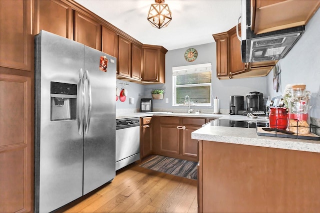 kitchen with brown cabinets, stainless steel appliances, light stone countertops, and light wood-style flooring