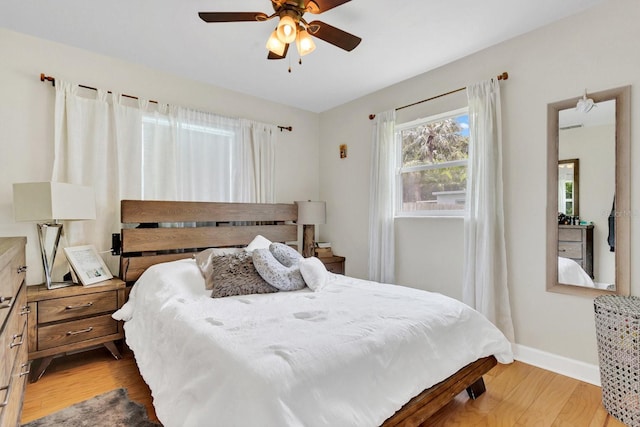 bedroom with a ceiling fan, light wood finished floors, and baseboards