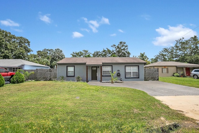 ranch-style house with stucco siding, fence, concrete driveway, and a front lawn