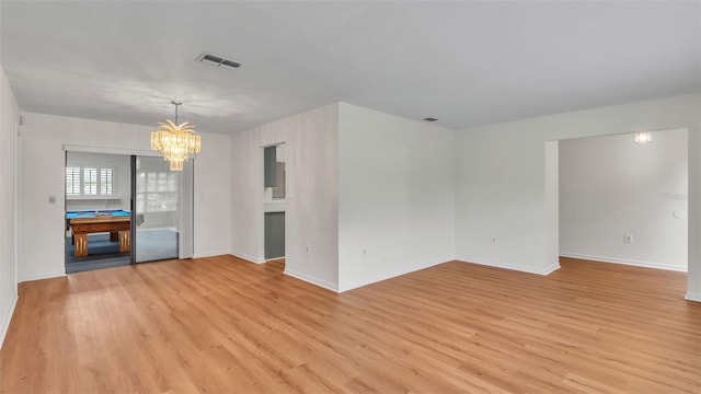 unfurnished living room featuring an inviting chandelier and light hardwood / wood-style floors