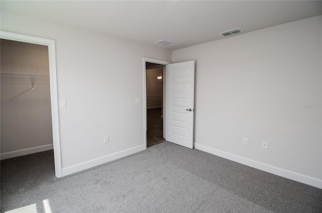 unfurnished bedroom with a walk in closet, carpet floors, and a closet