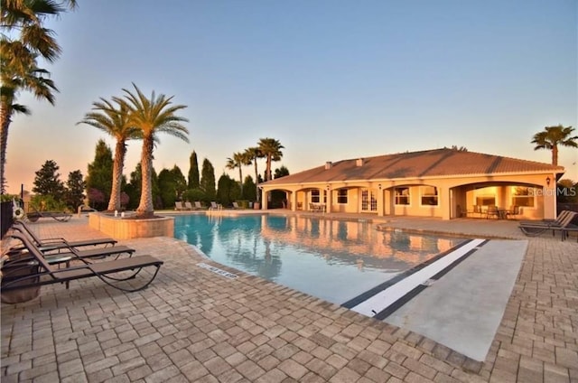 pool at dusk featuring a patio