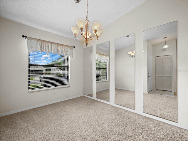 interior space with lofted ceiling, a textured ceiling, carpet flooring, baseboards, and a chandelier