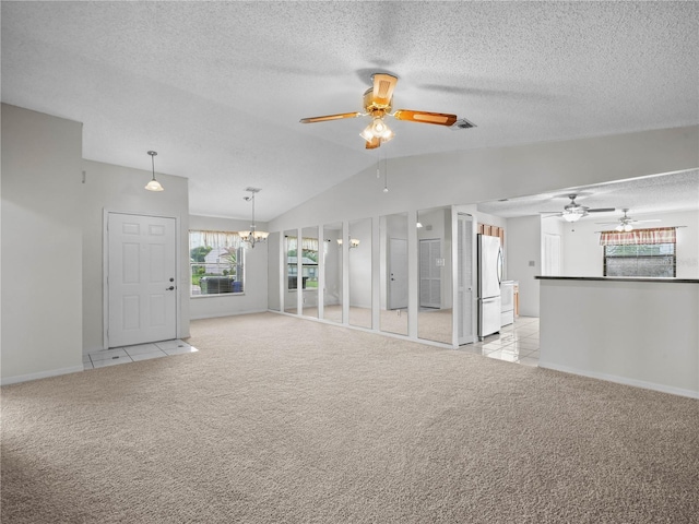 unfurnished living room with a textured ceiling, lofted ceiling, light colored carpet, and ceiling fan with notable chandelier