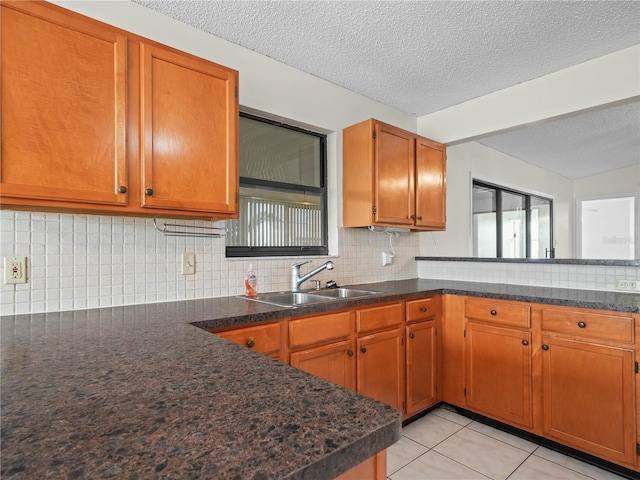 kitchen with a wealth of natural light, decorative backsplash, brown cabinets, and a sink