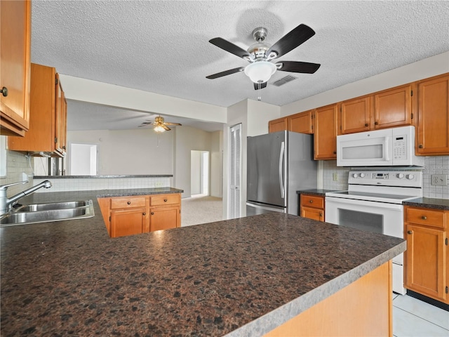 kitchen featuring a sink, dark countertops, white appliances, a peninsula, and decorative backsplash