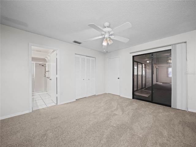 unfurnished bedroom with visible vents, carpet, a ceiling fan, and a textured ceiling