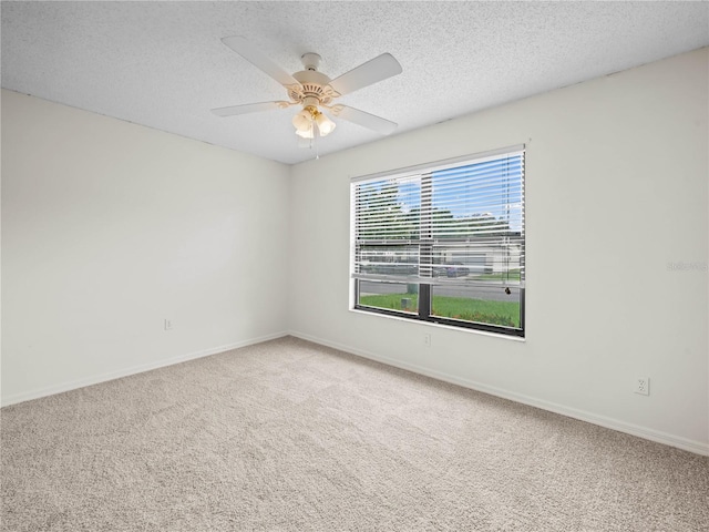 spare room with a ceiling fan, carpet, baseboards, and a textured ceiling